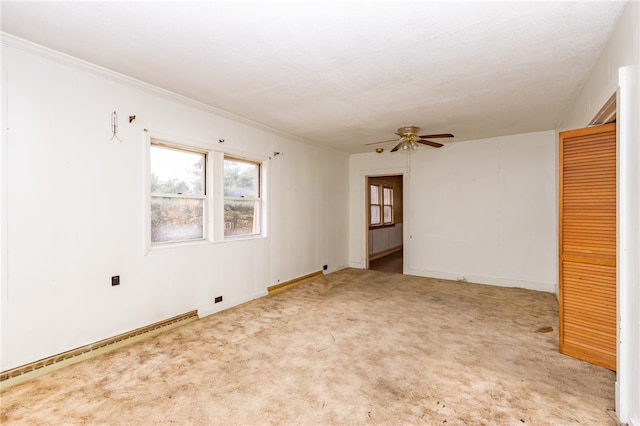 empty room featuring ceiling fan, crown molding, and light colored carpet