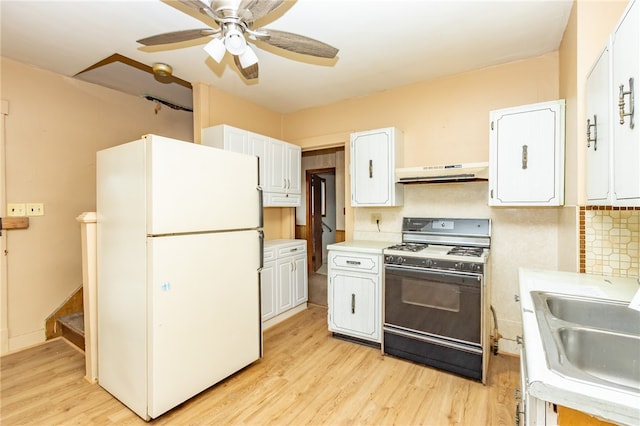 kitchen featuring gas range, white fridge, white cabinetry, and range hood