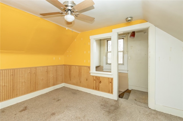 additional living space with wood walls, carpet floors, vaulted ceiling, and ceiling fan