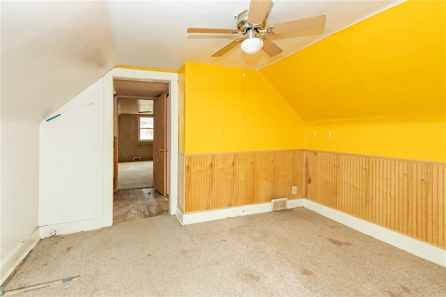 bonus room featuring carpet, ceiling fan, lofted ceiling, and wood walls