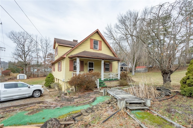 view of front of house featuring covered porch and a storage shed