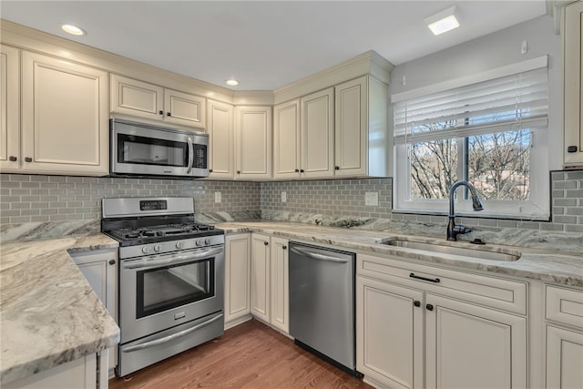 kitchen with decorative backsplash, appliances with stainless steel finishes, light stone counters, sink, and dark hardwood / wood-style floors