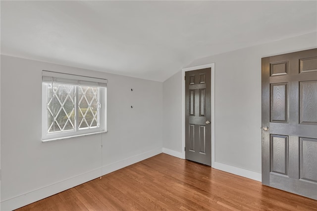 unfurnished room featuring hardwood / wood-style floors and vaulted ceiling