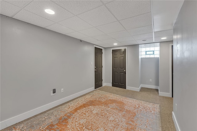 carpeted spare room featuring a drop ceiling