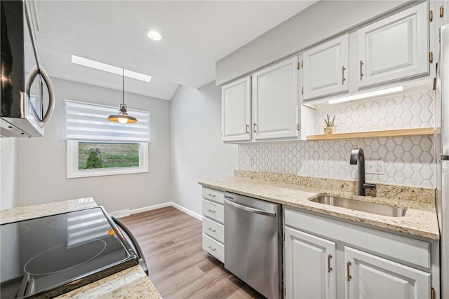 kitchen with appliances with stainless steel finishes, sink, decorative light fixtures, white cabinets, and light hardwood / wood-style floors