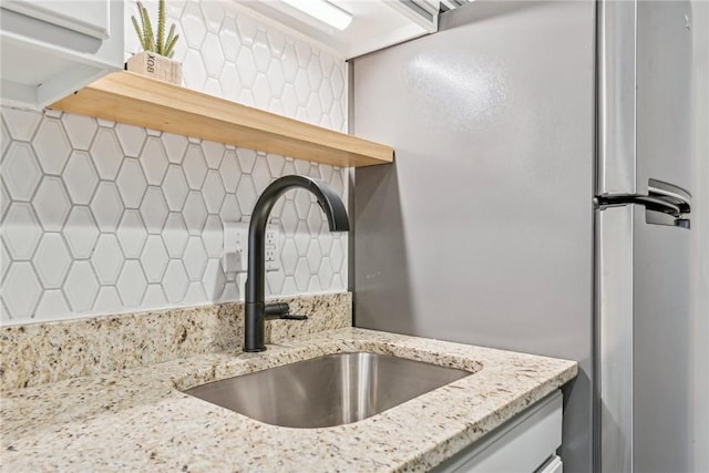 kitchen with decorative backsplash, light stone counters, and sink