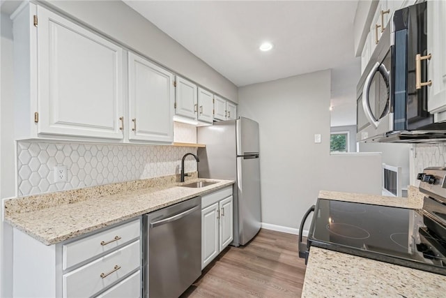 kitchen with white cabinets, light wood-type flooring, stainless steel appliances, and sink