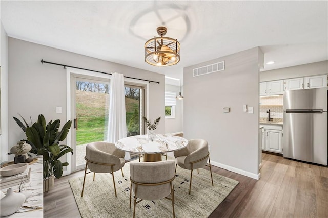 dining space with an inviting chandelier, dark wood-type flooring, and sink