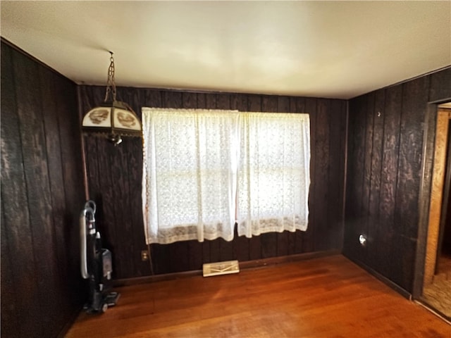 spare room featuring dark hardwood / wood-style floors, a wealth of natural light, and wooden walls