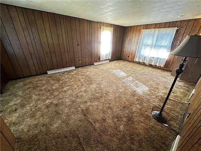 carpeted empty room featuring wood walls