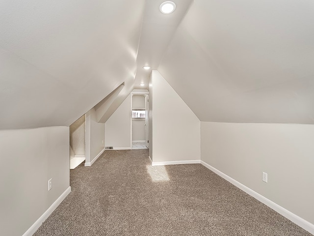 bonus room featuring dark colored carpet and lofted ceiling