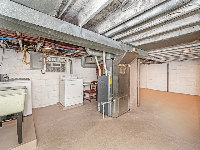 basement featuring washing machine and dryer, electric panel, heating unit, and sink