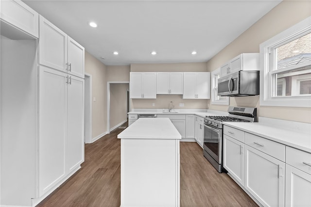 kitchen featuring hardwood / wood-style floors, a center island, white cabinets, and stainless steel appliances