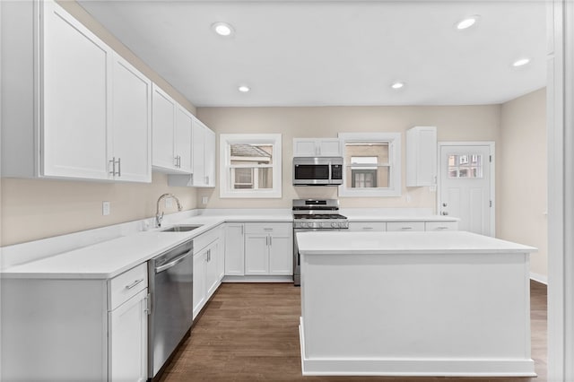 kitchen featuring white cabinetry, sink, dark wood-type flooring, a kitchen island, and appliances with stainless steel finishes