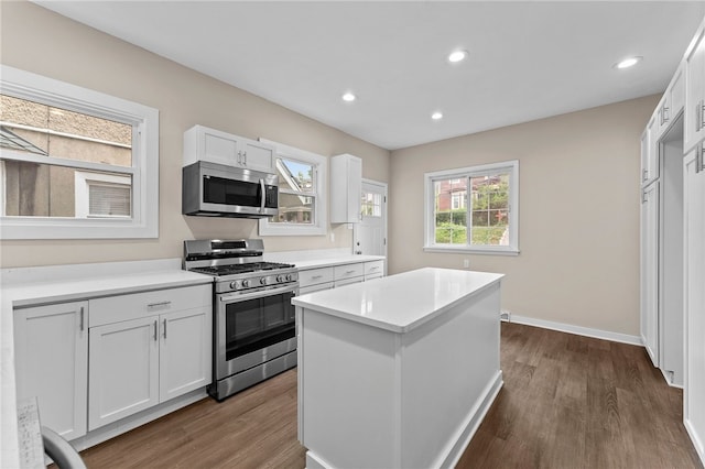 kitchen featuring appliances with stainless steel finishes, a center island, white cabinetry, and dark wood-type flooring