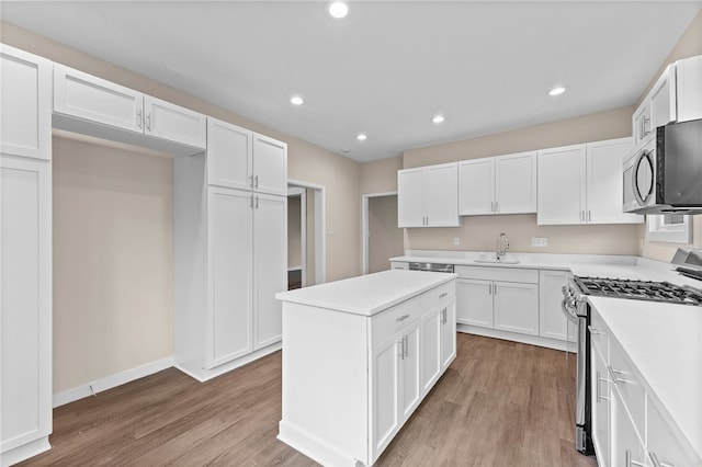 kitchen with stainless steel appliances, light hardwood / wood-style flooring, white cabinetry, and sink