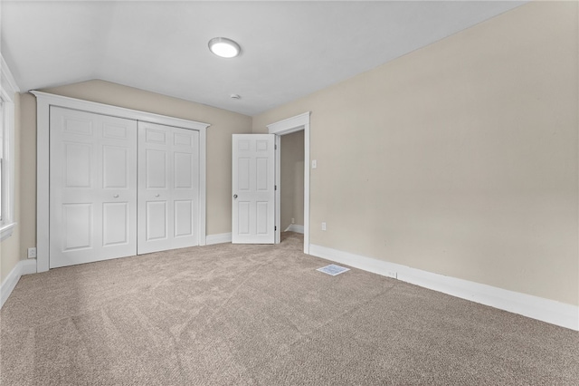 unfurnished bedroom with carpet, vaulted ceiling, and a closet