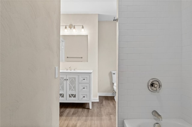 full bathroom featuring hardwood / wood-style floors, vanity, toilet, and tiled shower / bath