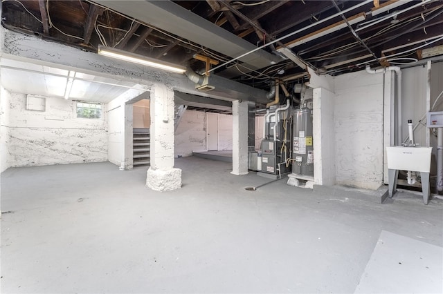 basement featuring gas water heater, sink, and heating unit