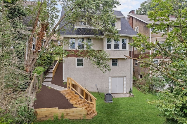 back of property with central AC unit and a lawn