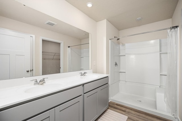 bathroom with hardwood / wood-style floors, vanity, a textured ceiling, and walk in shower