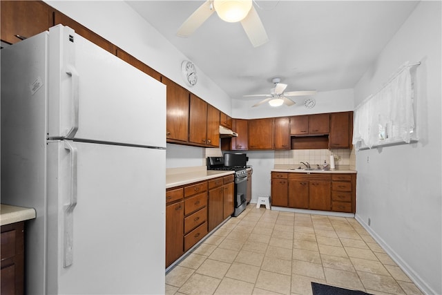 kitchen featuring gas stove, white fridge, sink, backsplash, and ceiling fan