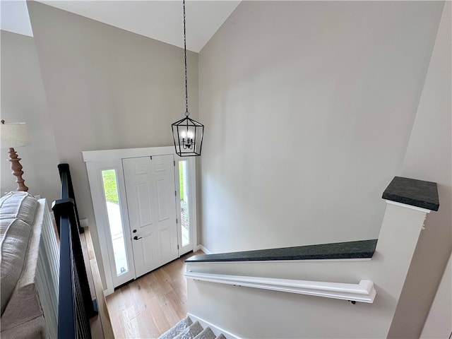 foyer entrance featuring a chandelier, lofted ceiling, and light hardwood / wood-style flooring