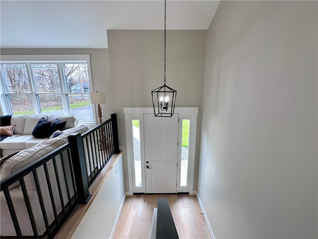 foyer with a healthy amount of sunlight, light hardwood / wood-style floors, and an inviting chandelier