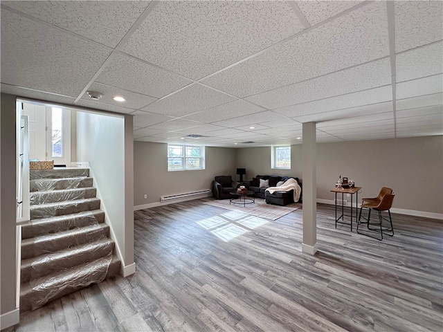 basement with a paneled ceiling, wood-type flooring, and a baseboard radiator