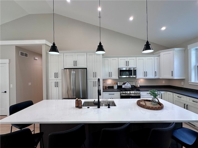 kitchen featuring a kitchen breakfast bar, a large island with sink, pendant lighting, and appliances with stainless steel finishes