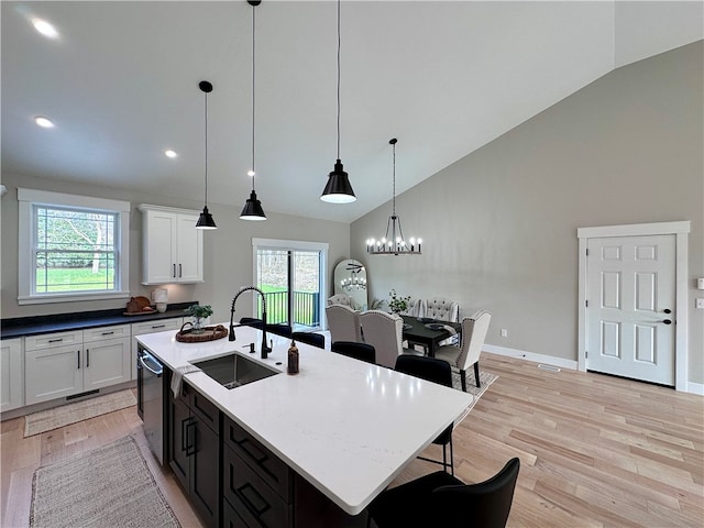 kitchen featuring white cabinetry, sink, light hardwood / wood-style floors, and decorative light fixtures