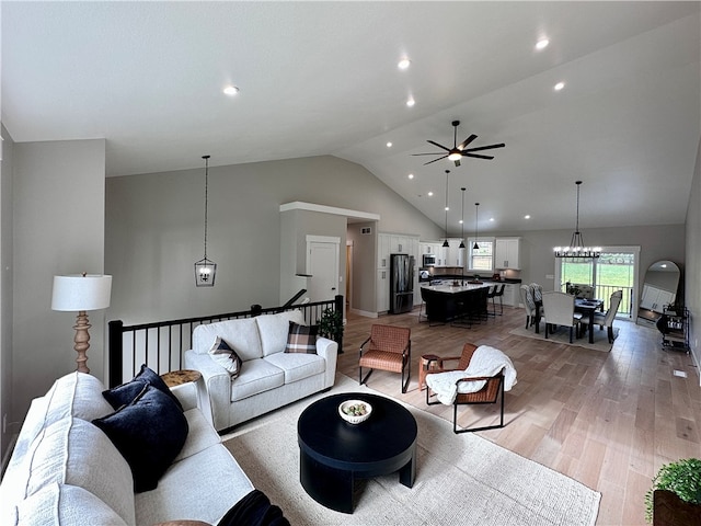 living room featuring lofted ceiling, light wood-type flooring, and ceiling fan with notable chandelier