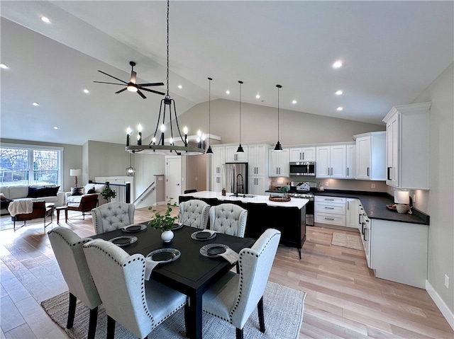 dining area with ceiling fan with notable chandelier, high vaulted ceiling, light hardwood / wood-style flooring, and sink