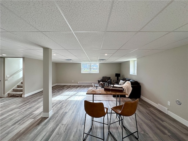 interior space with hardwood / wood-style floors, baseboard heating, and a drop ceiling