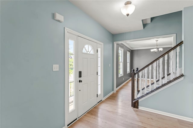 foyer entrance with light hardwood / wood-style floors and an inviting chandelier