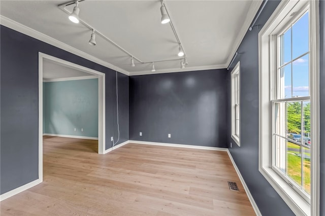 spare room featuring plenty of natural light, light hardwood / wood-style floors, ornamental molding, and rail lighting