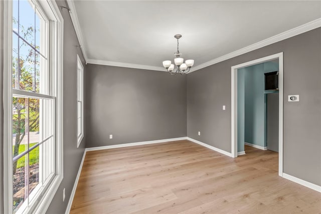 empty room featuring a healthy amount of sunlight, crown molding, a chandelier, and light hardwood / wood-style floors