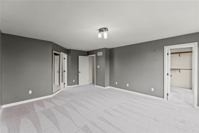 unfurnished bedroom featuring light colored carpet, a spacious closet, and a closet