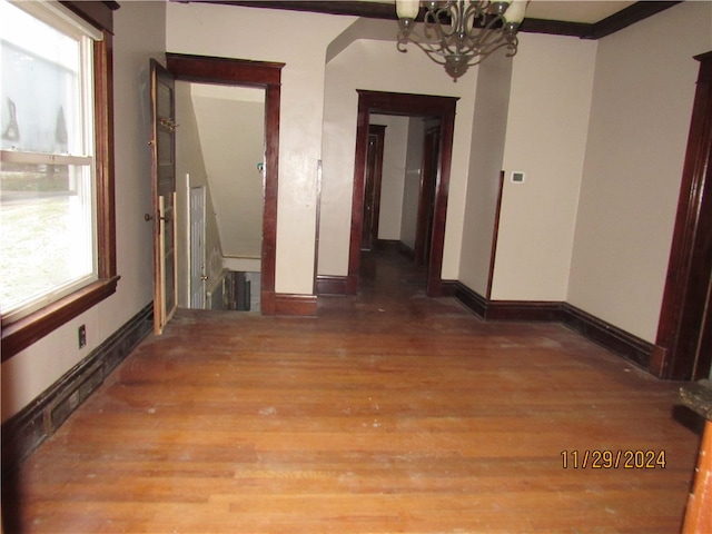 hall featuring crown molding, hardwood / wood-style floors, and a notable chandelier