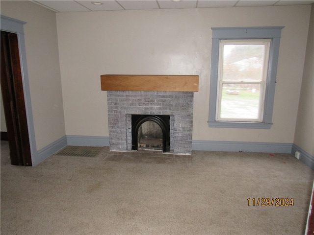 unfurnished living room with carpet, a paneled ceiling, and a brick fireplace