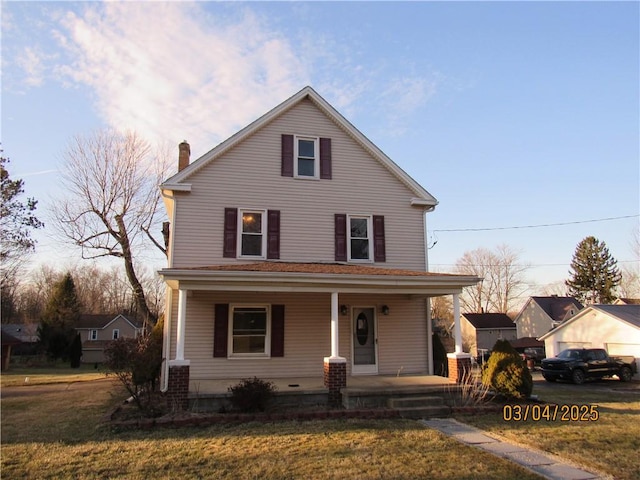 view of front of house featuring a chimney, covered porch, and a front yard