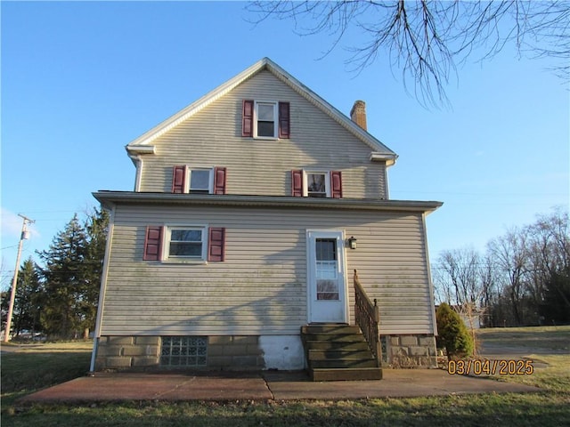 rear view of house with entry steps and a chimney