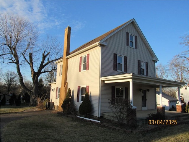 exterior space featuring a lawn, covered porch, and a chimney