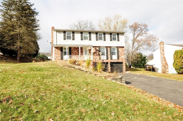 view of front of home with a front yard, a garage, and covered porch