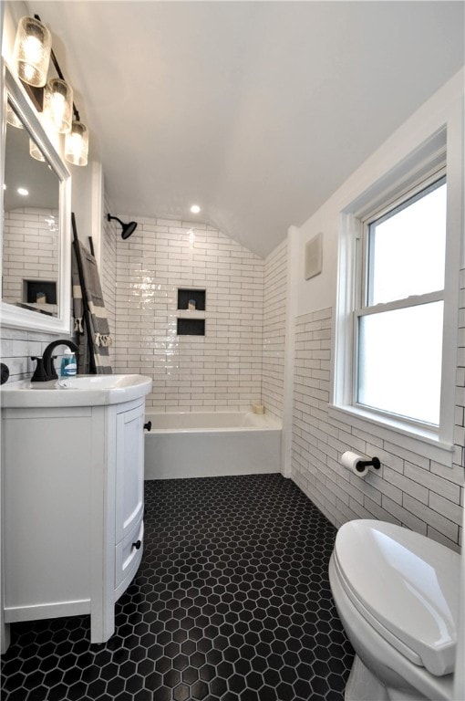 full bathroom featuring vanity, tile walls, tile patterned flooring, toilet, and lofted ceiling