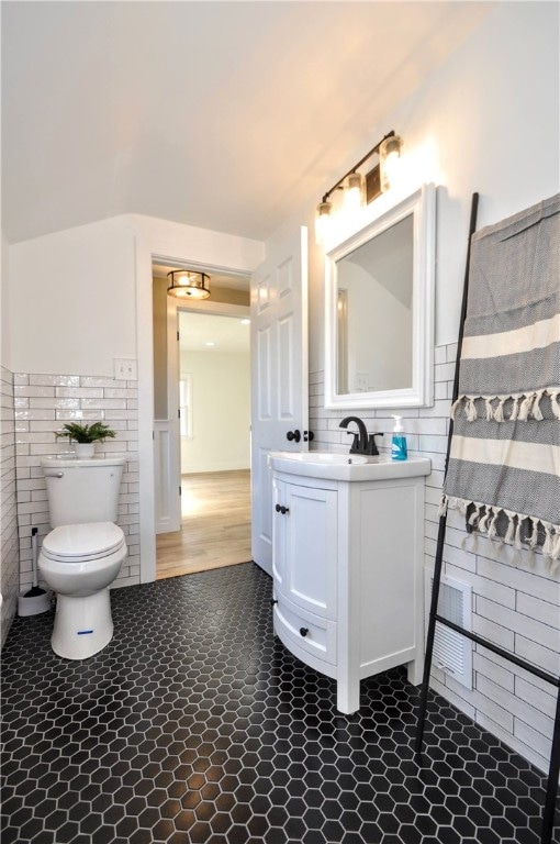 bathroom featuring vanity, toilet, and tile walls