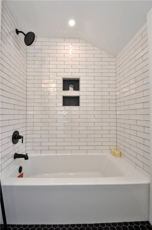 bathroom featuring tiled shower / bath combo and lofted ceiling