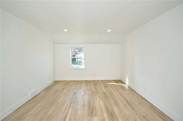 empty room with light wood-type flooring and lofted ceiling