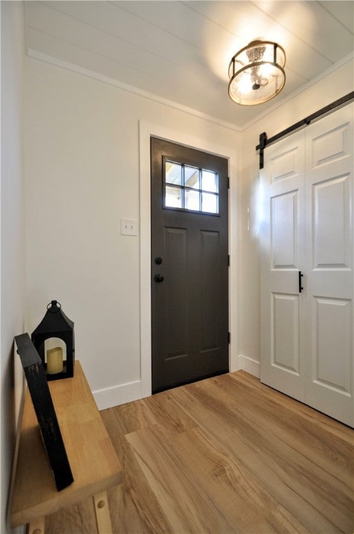 entryway with a barn door, crown molding, and wood-type flooring