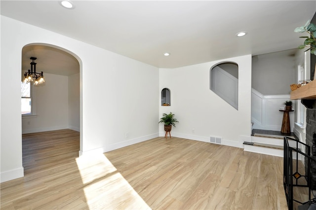 unfurnished living room with a fireplace, light hardwood / wood-style flooring, and a chandelier